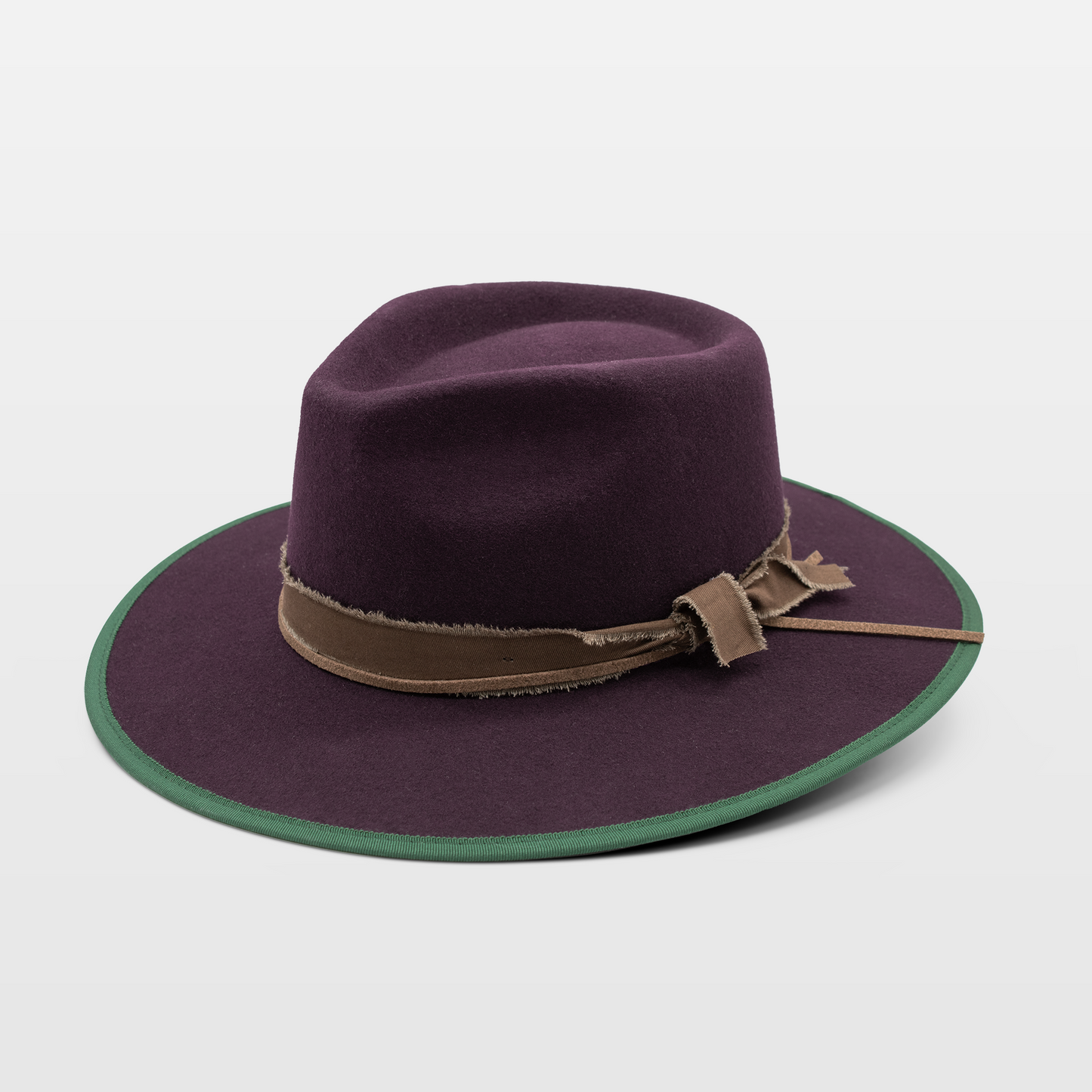 Purple wide-brim hat with green trim and a brown band with frayed detail