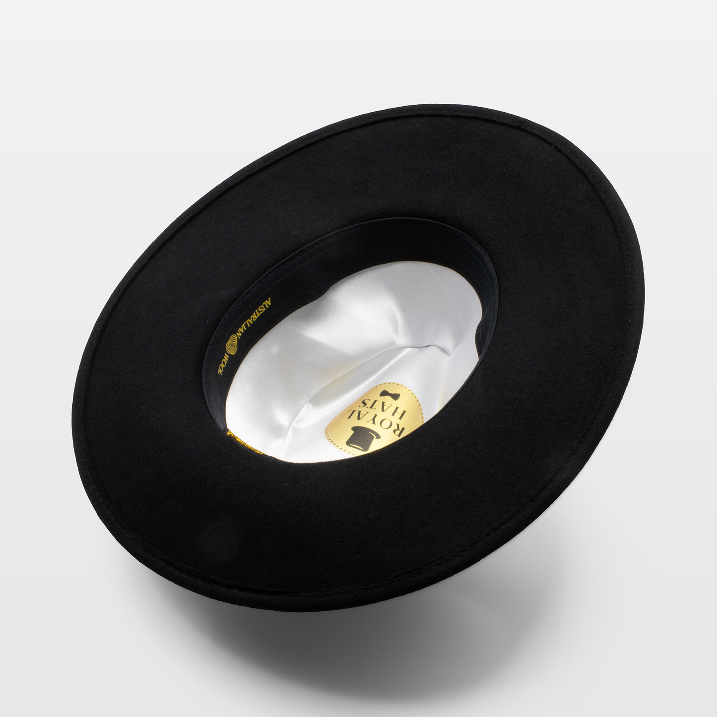 Black wide-brimmed hat shown upside down to display the white satin interior