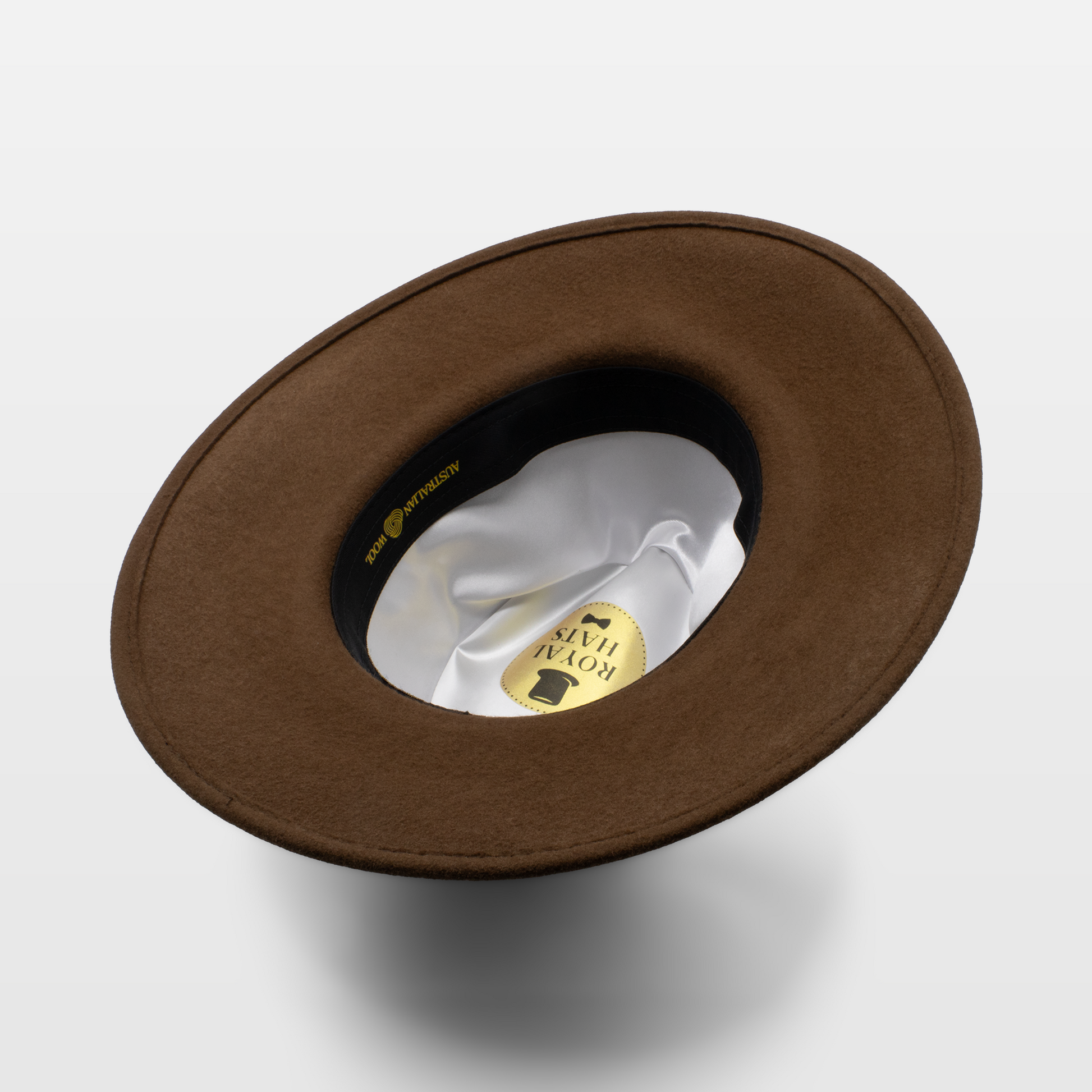 Brown wide-brimmed hat shown upside down to display the white satin interior