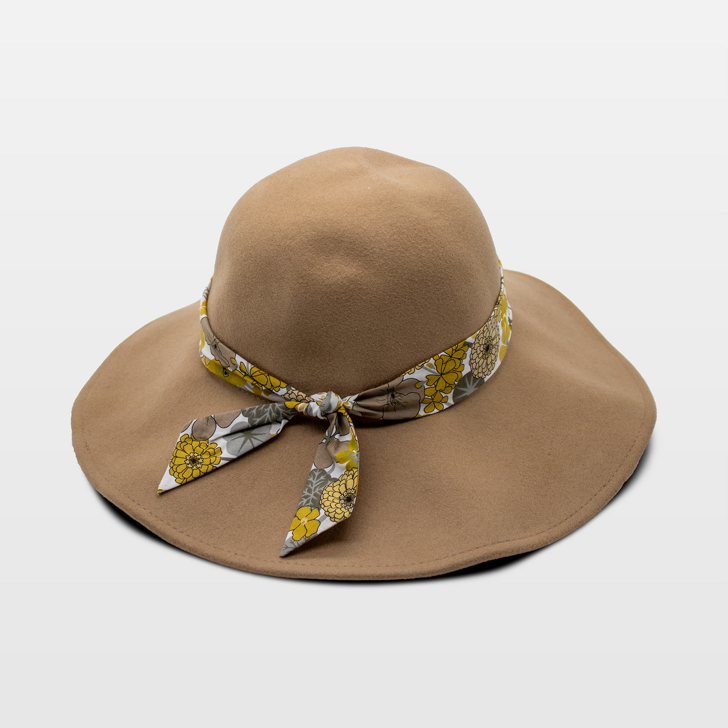 A stylish tan hat with a wide brim, adorned with a floral-patterned band tied in a bow