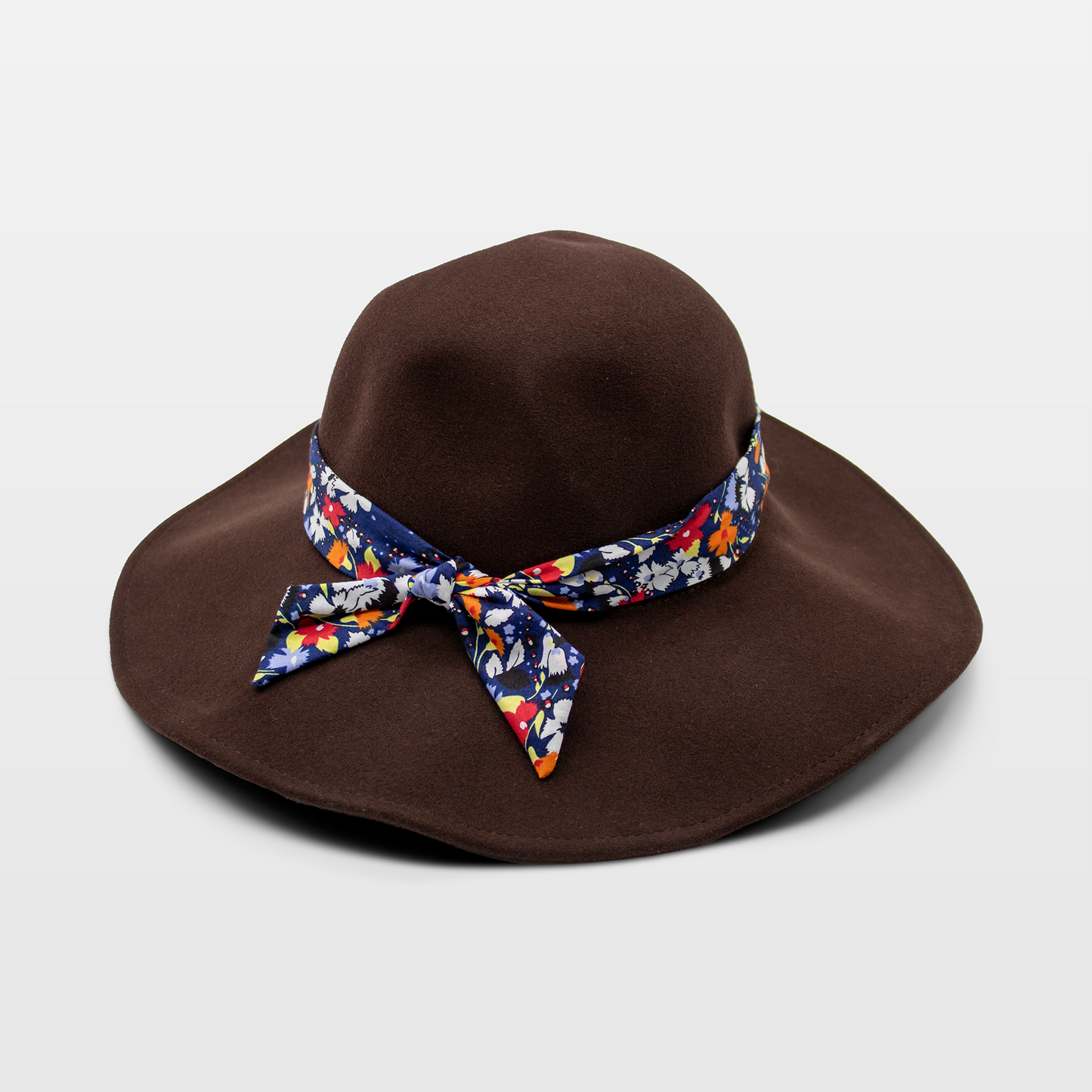 A stylish dark brown hat with a wide brim, with a colorful floral-patterned band tied in a bow