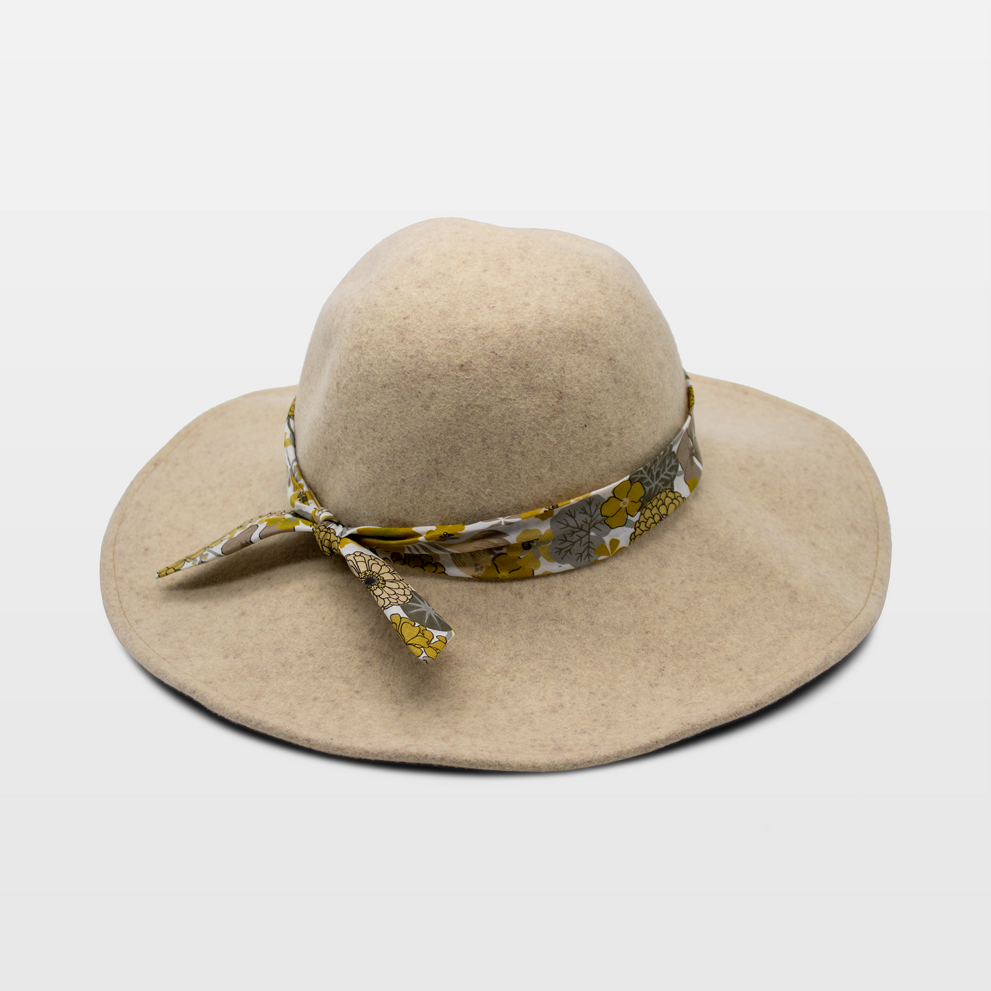 A stylish beige hat with a wide brim, adorned with a floral-patterned band tied in a bow